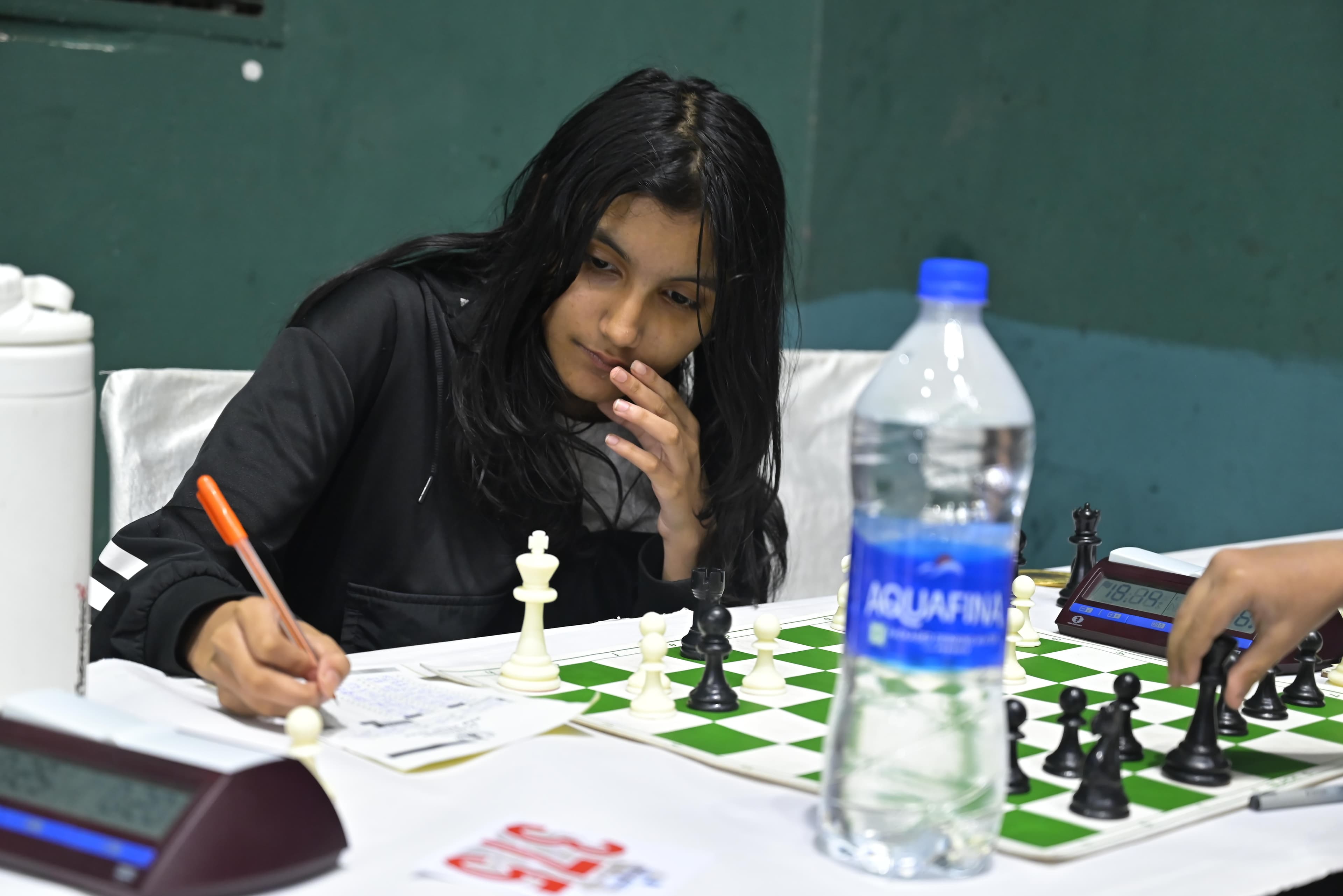 Chess player writing notation beside a tournament board
